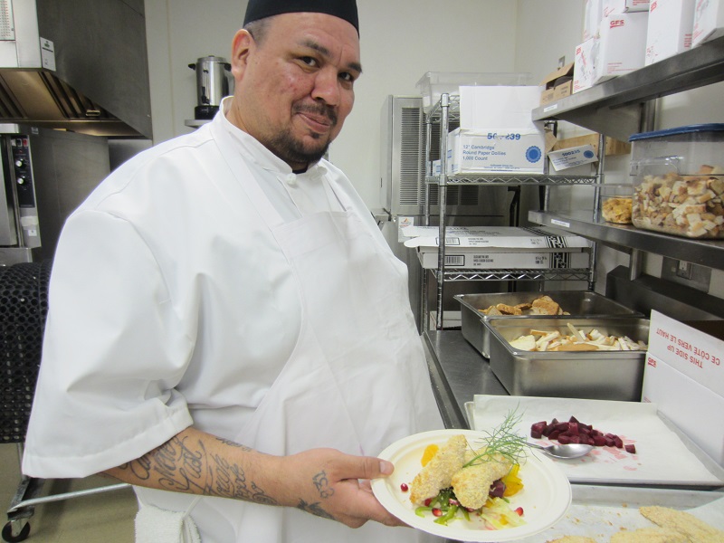 Norman serves a plate of food to clients at Belkin House