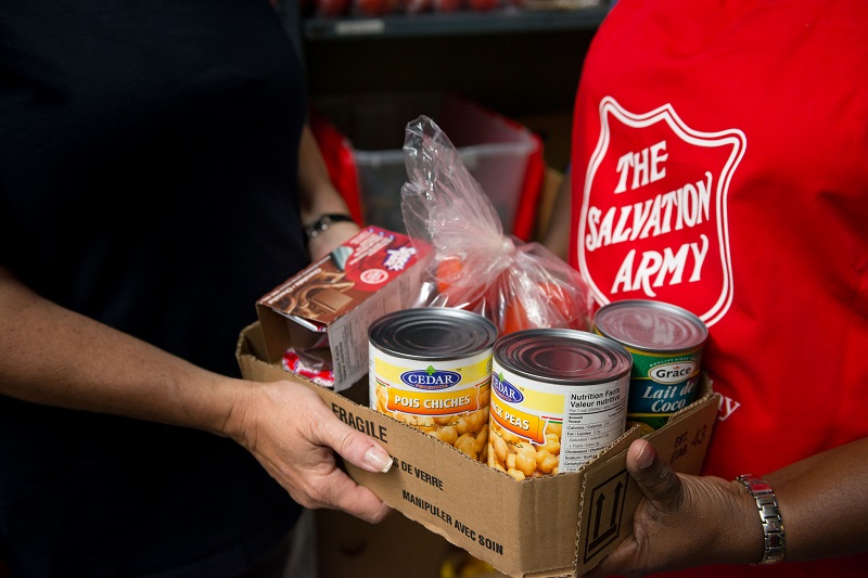 Salvation Army worker hands canned food and other items to client