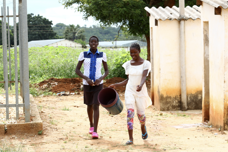 Zambian students collecting clean water in bucket