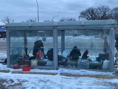 People experiencing homelessness seek refuge in bus shelter