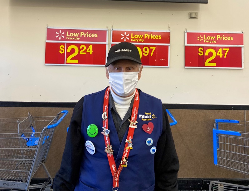 Walmart employee with Walmart vest stands with mask