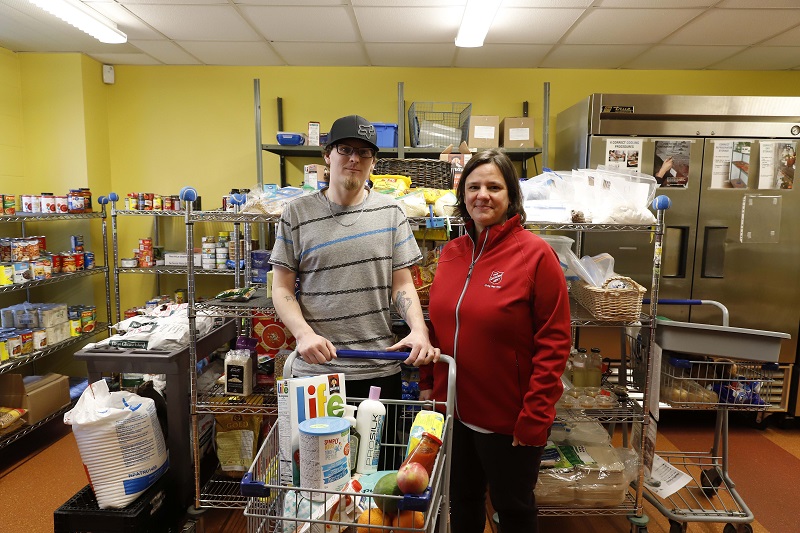 Chris with food and practical items in cart alongside Salvation Army worker