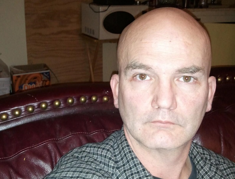 Balding male sits on couch