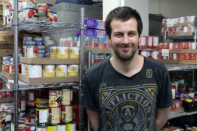 Jimmy stands in front of food at Salvation Army food bank