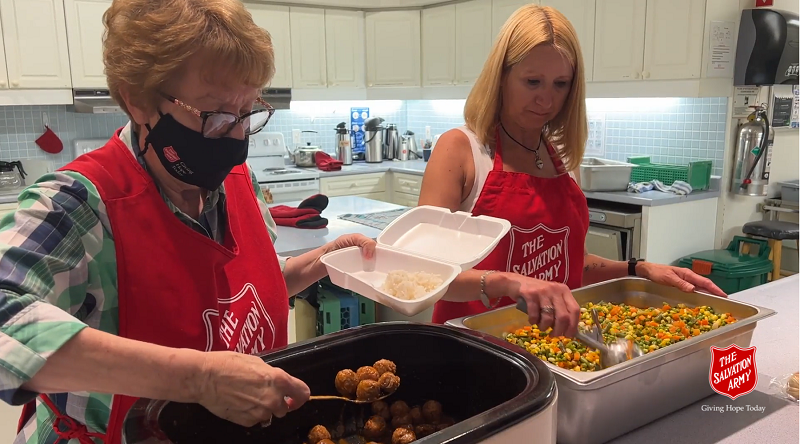 Two volunteers prepare hot meals for delivery