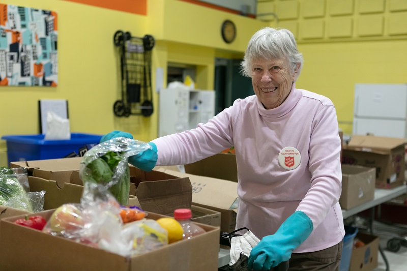 Salvation Army female volunteer packs fresh food hamper