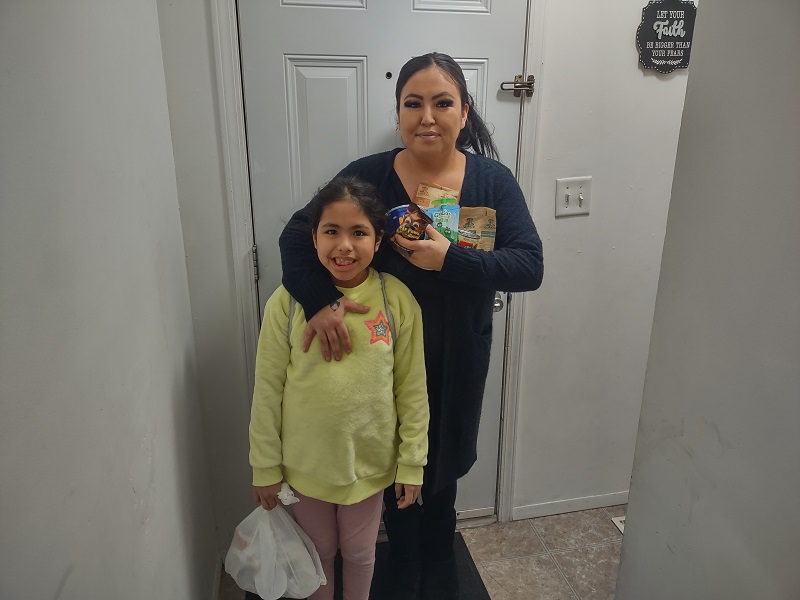 Mother and daughter hold food from backpack meal program