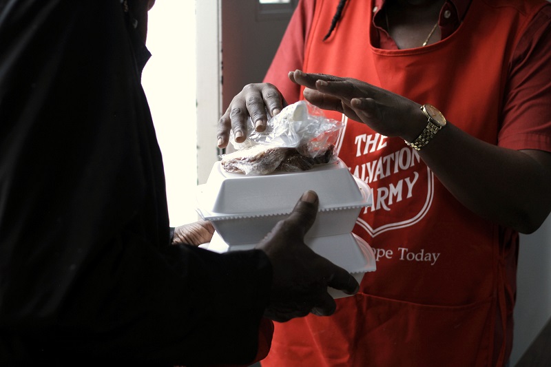Salvation Army worker hands over boxed meal to client