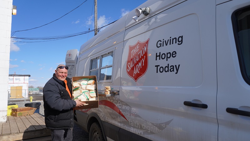 volunteer stands by mobile outreach van with box of sandwiches
