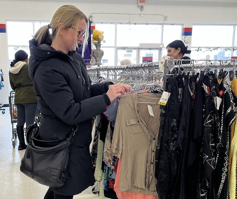 Sylwia browses through clothes racks at the store