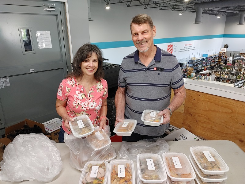 Volunteers hold prepared meals ready for delivery