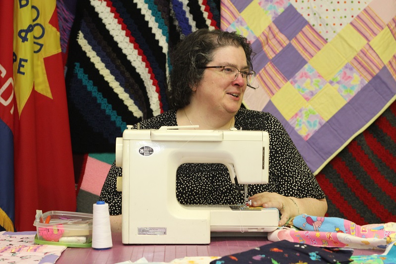 Lynette sits at her sewing machine
