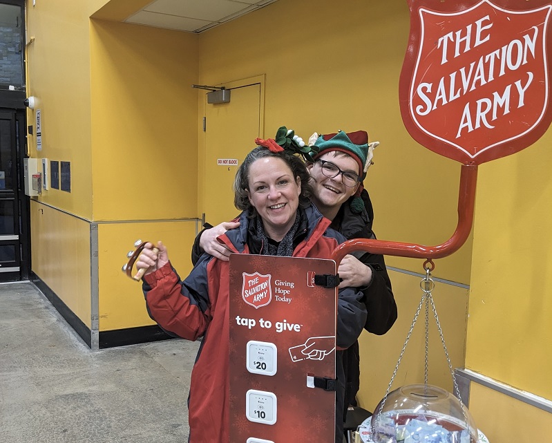 Kelley and Jordan stand by Salvation Army Christmas kettle