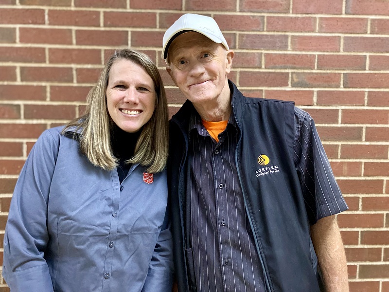 Leonard right, wearing baseball cap; Salvation Army female worker in blue branded shirt left