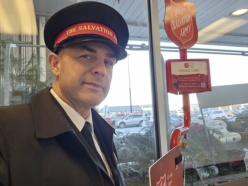 Spencer, in Salvation Army uniform, stands at kettle