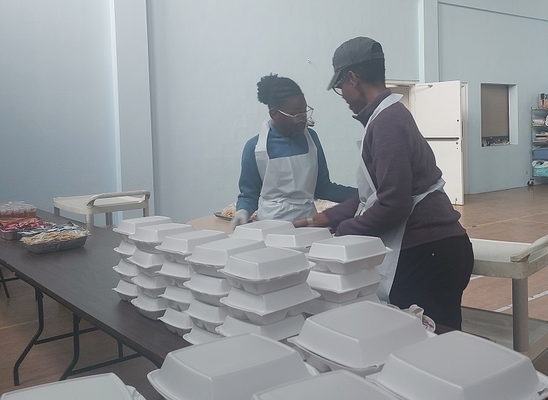 Two volunteers pack food for distribution