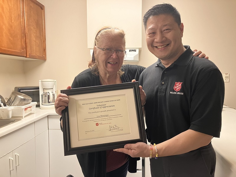 Lisa holds certificate of appreciation alongside Salvation Army worker