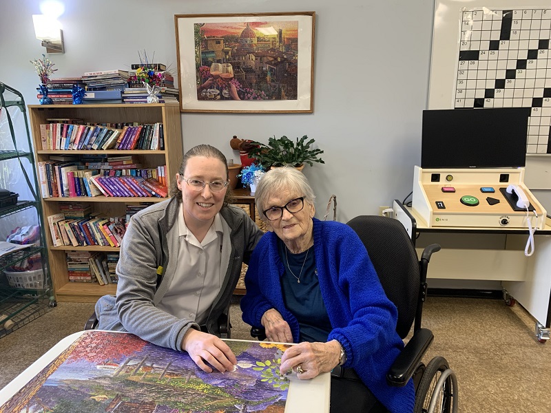 Theresa sits in front of puzzle with Major Lynda beside her