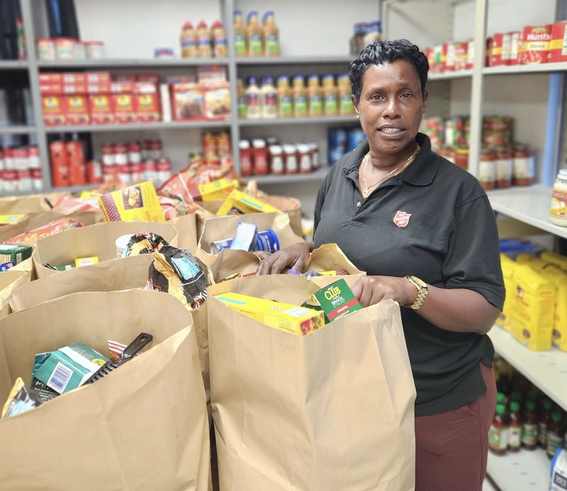 Kellie stands at food bank with food bags for delivery