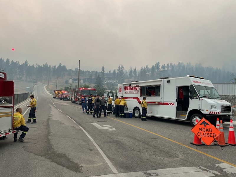 Emergency disaster services vehicle serves first responders while smoke looms in back ground