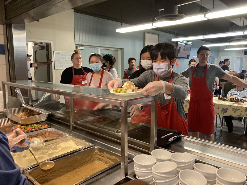 Kitchen staff serve hot meals to vulnerable guests