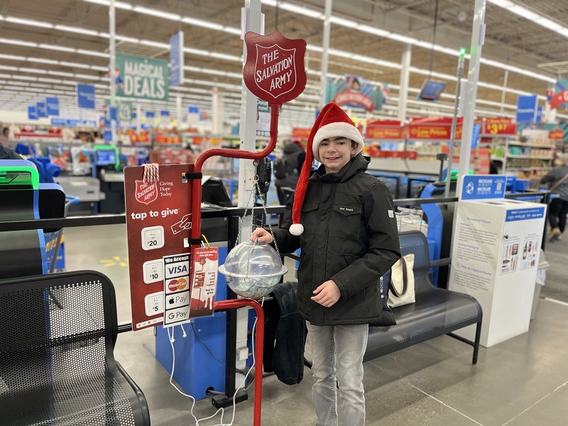 Justin puts money in Salvation Army kettle