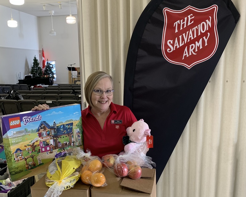 Salvation Army worker holds lego, stuffed toys and food items for distribution