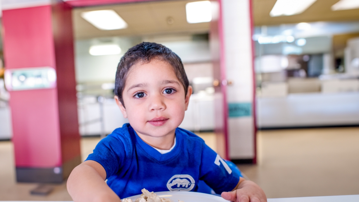 young boy sits in front of meal