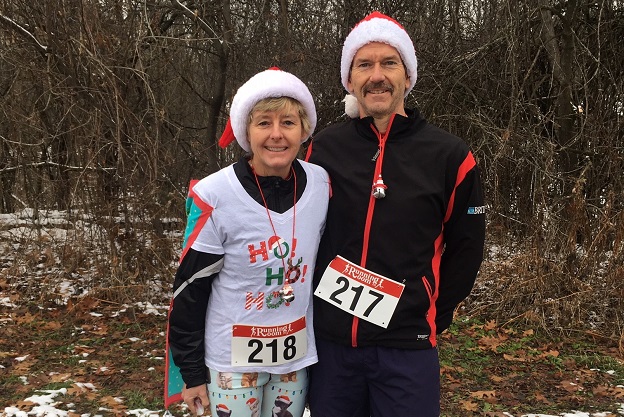 Stephane and her husband in santa hats and festive shirts