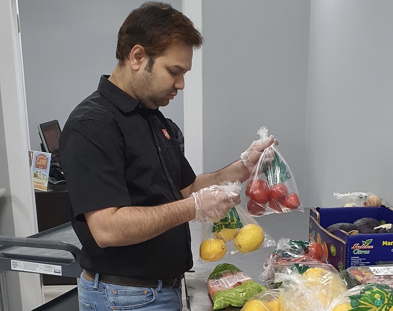Salvation Army worker puts fruit and vegetable into food box
