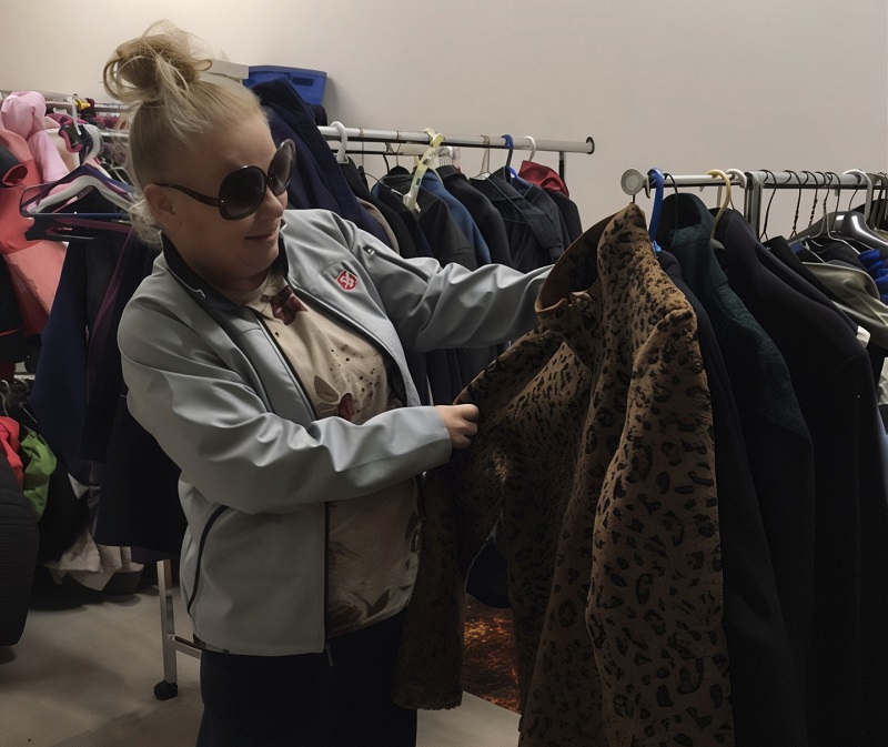 Client chooses winter coat off rack of coats