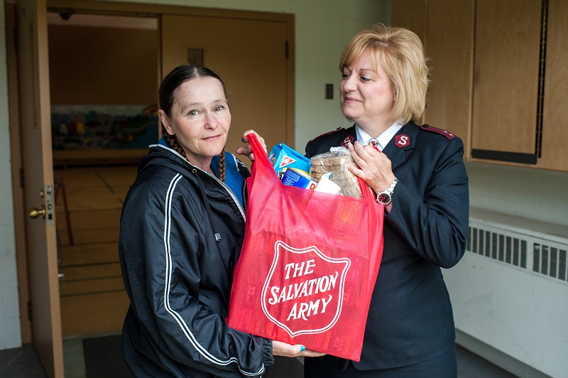 Salvation Army worker gives bag of food items to client