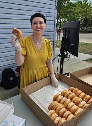Board member, Sandra Hawes, serves doughnuts to community members
