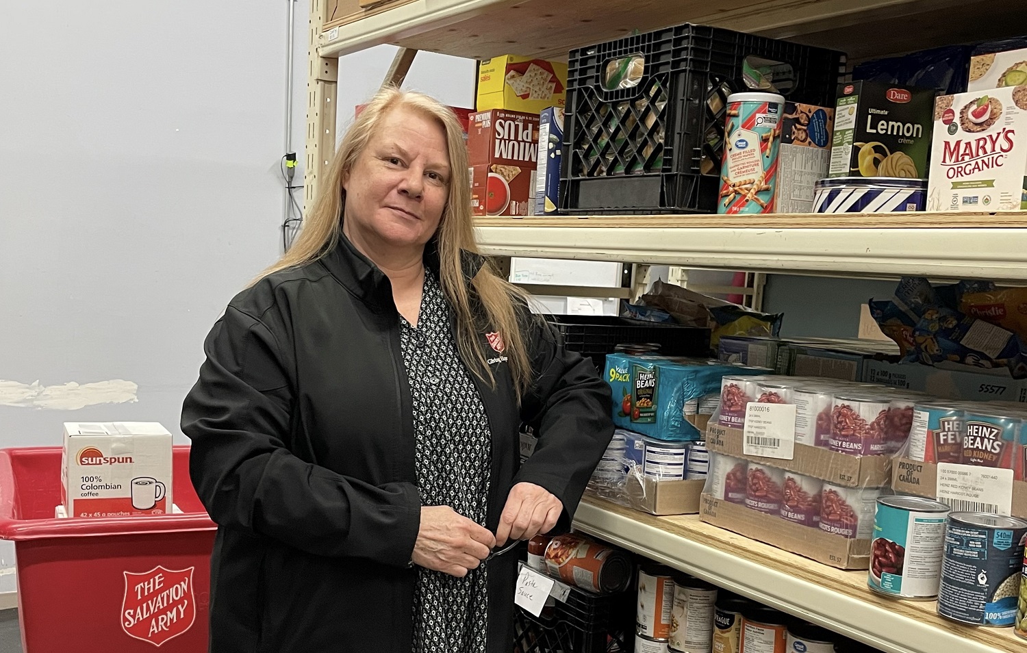 Caroline stands in front of food bank shelves