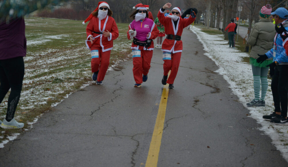 3 runners dressed as santa claus running down a road